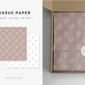 Puede incluir: Papel de seda con un delicado patr&oacute;n de hojas blancas sobre un fondo rosa claro. El papel de seda est&aacute; doblado y colocado dentro de una caja de cart&oacute;n marr&oacute;n. La caja tiene una pegatina blanca con el texto "&iexcl;gracias!" en ella.