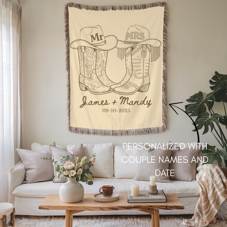 Pu&ograve; includere: Coperta in tessuto color crema con un design di stivali e cappello da cowboy. La coperta ha un bordo con frange e include il testo "Mr" e "Mrs" sui cappelli, insieme a nomi e una data. Un pezzo decorativo per la casa.