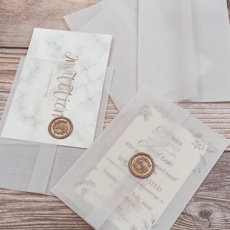 May include: Two wedding invitations with a marble design and a wax seal. The invitations are in clear envelopes with a floral design.