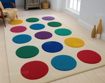 Puede incluir: Una alfombra rectangular de color crema con grandes lunares de colores. Los lunares son de varios colores, incluyendo rojo, azul, verde, amarillo, morado y turquesa. La alfombra está colocada sobre un suelo de madera clara.