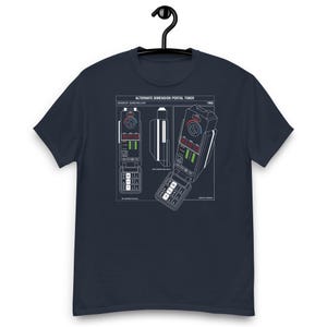 May include: A navy blue short-sleeve t-shirt featuring a white technical line drawing of an Alternate Dimension Portal Timer. The graphic includes the text "ALTERNATE DIMENSION PORTAL TIMER," "DESIGN BY: QUINN MALLORY," and "1995" with detailed schematics.