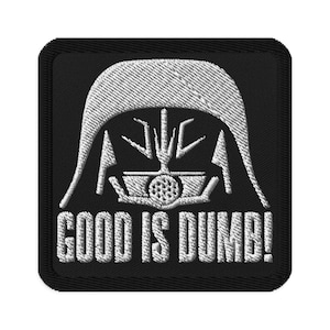 May include: Black square patch featuring a white embroidered design of a helmet and the text "GOOD IS DUMB!". The design is a stylized representation of a character's helmet from a science fiction film.