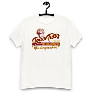May include: White t-shirt with the Louis Tully Tax and Accounting logo in burgundy and gold. The design includes a portrait of Louis Tully, the text "Louis Tully Tax and Accounting Since 1984", and the phrase "Who does your Taxes?"