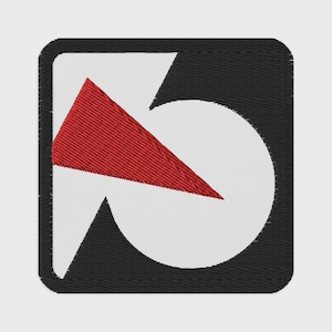 May include: Embroidered patch featuring a geometric design. The patch has a black square border with rounded corners. Inside, a white shape forms a partial circle and a black triangle. A red triangle is positioned over the white shape.