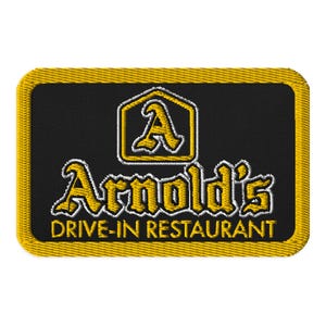Puede incluir: Parche bordado con fondo negro y borde amarillo. El parche presenta las palabras "Arnold's Drive-In Restaurant" en una fuente estilizada. Encima del nombre hay un logotipo amarillo y blanco con la letra "A".