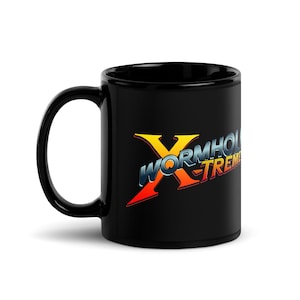May include: Black ceramic mug featuring the text "WORMHOLE X-TREME" in a colorful, stylized design. The mug has a large handle and a glossy finish. The design includes a large yellow "X" and the words "WORMHOLE X-TREME" in blue, orange, and red.