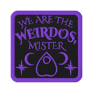 Puede incluir: Parche bordado con fondo negro y borde morado. El texto "WE ARE THE WEIRDOS, MISTER" está bordado en morado, junto con una ouija, medias lunas y estrellas.