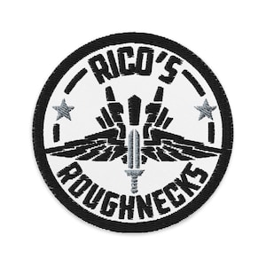 May include: Black and white embroidered patch with a circle design. The center features a stylized sword with wings and the text "RICO'S ROUGHECKS" around the outside.