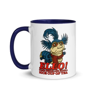 May include: White ceramic mug with a blue rim and handle. The mug features a cartoon illustration of a blue and red creature with the text "Ello! Come inside and have a nice cup of tea."