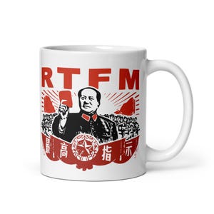 May include: A white ceramic mug featuring a red and black graphic print. The design displays the text RTFM at the top, a central figure holding a red book, and a banner at the bottom with the Chinese characters 最高指示 and a star emblem.