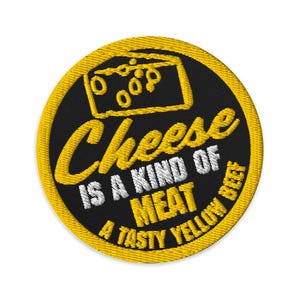 May include: Embroidered patch with a yellow border and a black center. The patch features a yellow cheese illustration and text that reads "Cheese is a kind of meat, a tasty yellow beef."