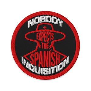 May include: Embroidered patch with a red border and a black center. The patch features the text "NOBODY EXPECTS THE SPANISH INQUISITION" in white and red, surrounding a red graphic of a person in a hat.