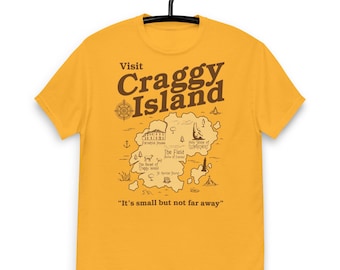 May include: A yellow t-shirt with a brown graphic of a map of Craggy Island. The map includes landmarks like the Parental House, The Field, and the Holy Slope of Clondichert. The text "Visit Craggy Island" and "It's small but not far away" are printed on the shirt.