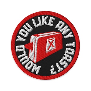 Könnte beinhalten: Gestickter Aufnäher mit einem rot-weißen Toaster-Design auf schwarzem Hintergrund, umgeben von dem Text "WOULD YOU LIKE ANY TOAST?". Der Aufnäher hat einen roten Rand.