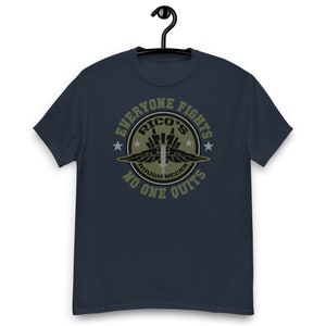 May include: A navy blue t-shirt with a green circle graphic. The graphic features a fighter jet, the text "Rico's", and the words "Everyone Fights, No One Quits".