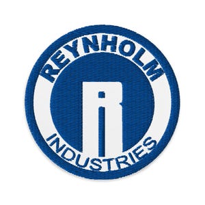 Könnte beinhalten: Gestickter Aufnäher mit blauem Hintergrund und weißem Rand. Der Text "REYNHOLM INDUSTRIES" ist oben und unten um den Kreis gebogen. Ein großes weißes "R" befindet sich in der Mitte des Aufnähers.