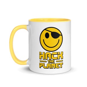 May include: White ceramic mug with a yellow interior and handle. The mug features a yellow smiley face with an eye patch and the words "HACK THE PLANET" in yellow block letters.