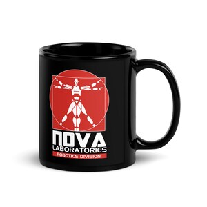 May include: A black ceramic mug featuring a white graphic of a robotic figure inside a red circle and square. Below the graphic, the text reads NOVA LABORATORIES ROBOTICS DIVISION in white and red lettering. The mug has a curved handle on the right.