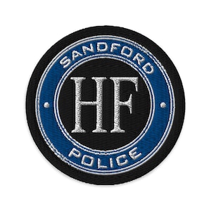 Peut inclure: Un écusson brodé noir et bleu avec le texte "SANDFORD POLICE" en cercle autour des lettres "HF".