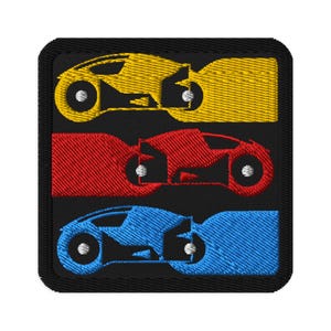 Puede incluir: Parche bordado con tres vehículos futuristas en amarillo, rojo y azul. Cada vehículo tiene un diseño único con ruedas circulares y una carrocería elegante, sobre un fondo negro.