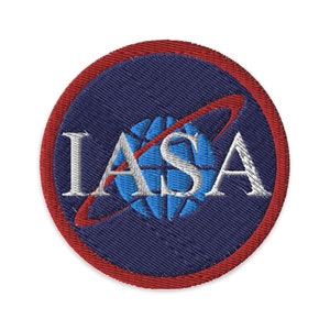 May include: A blue and white embroidered patch with the word "NASA" in white lettering and a red circle border.