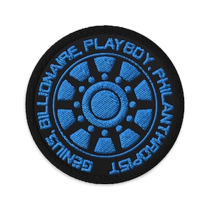 Op de afbeelding: Zwarte en blauwe geborduurde patch met de tekst "Genius Billionaire Playboy Philanthropist" in een cirkel rond een gestileerd blauw en zwart ontwerp.