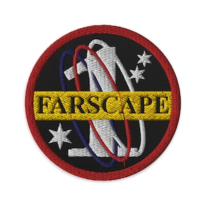 May include: A black and red embroidered patch with a white figure in the centre, surrounded by a blue and red ring. The text "FARSSCAPE" is written in yellow across the centre of the patch.