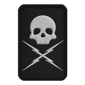 May include: Embroidered patch featuring a white skull above two crossed lightning bolts, set against a black rectangular background. The skull and lightning bolts have a textured appearance, giving a detailed look. The patch has a black border.