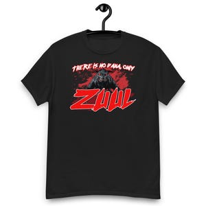 May include: A black short-sleeved t-shirt featuring a graphic print of a creature with glowing red eyes. Above the creature, the white text reads "THERE IS NO DANA, ONLY". Below, the word "ZUUL" is printed in large, bold red letters.