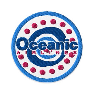 Puede incluir: Parche bordado con el texto "Oceanic AIRLINES" en azul y blanco, rodeado por un diseño circular azul y blanco con puntos rojos. El parche tiene un borde azul y es probablemente para una chaqueta o bolso.