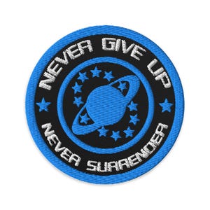 May include: A round, embroidered patch with a blue and black color scheme. The patch features the words "NEVER GIVE UP" and "NEVER SURRENDER" in white, surrounding a blue planet design with stars. The outer border is blue.