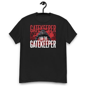 May include: A black short-sleeved t-shirt featuring a graphic print of a dark, snarling creature with glowing red eyes. Behind the creature is a red distressed background with the text "GATEKEEPER" in red and "I AM THE GATEKEEPER" in white.
