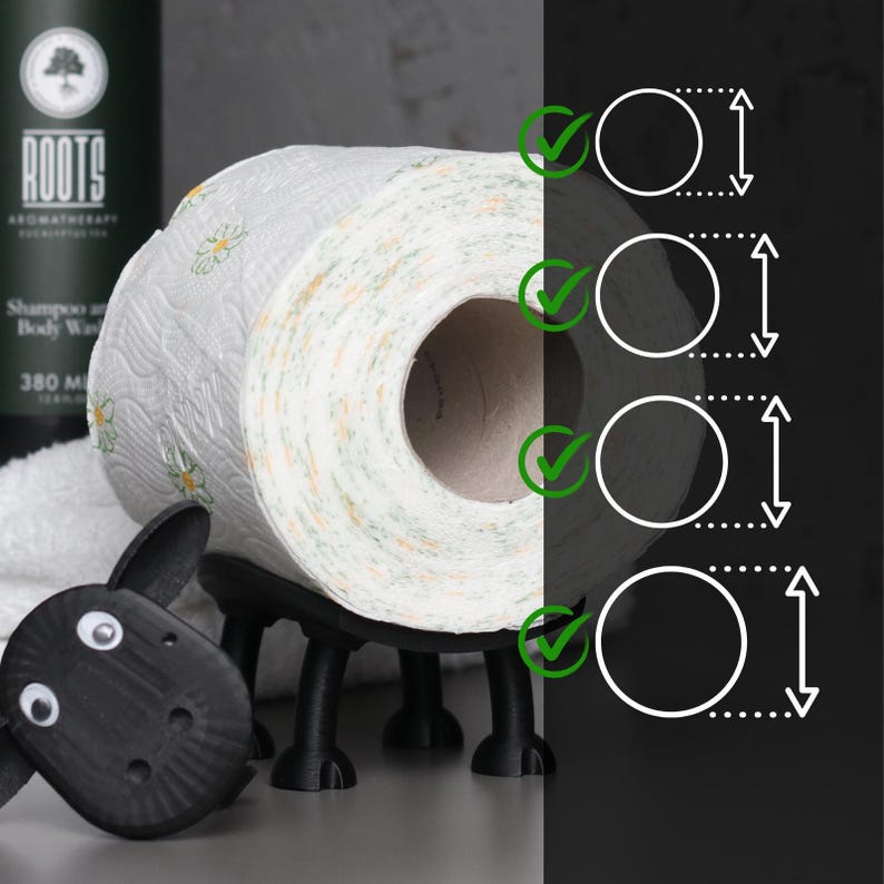 Op de afbeelding: Zwarte toiletpapierhouder in de vorm van een schaap met een rol wit toiletpapier met een bloemenpatroon. De houder heeft vier poten en een schattig gezicht.