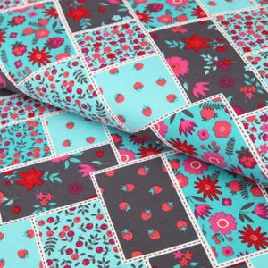 Könnte beinhalten: Ein Patchwork-Stoff mit einem sich wiederholenden Muster aus roten und rosa Blüten, grünen Blättern und roten Beeren auf türkisfarbenem Hintergrund. Der Stoff ist in Quadrate geschnitten und zu einem Patchwork-Muster zusammengenäht. Der Stoff ist auch in Grau erhältlich.