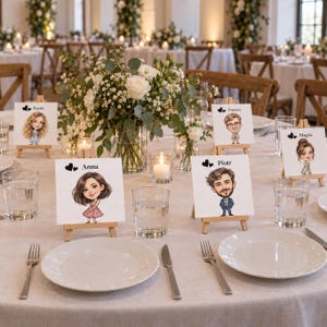 May include: A round dining table set with white plates, clear glasses, and silver cutlery. Small wooden easels hold white cards featuring cartoon-style illustrations of people named Kasia, Tomasz, Magda, Anna, and Piotr, each with two black hearts.