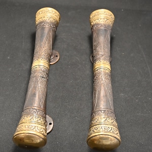 May include: A pair of ornate door handles with intricate designs. The handles are made of brass with a dark patina and gold accents.