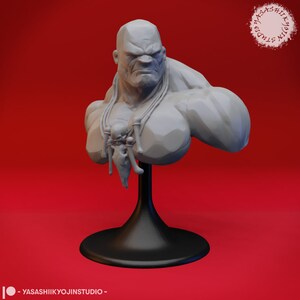Könnte beinhalten: Eine graue, 3D-gedruckte Büste einer muskulösen Figur mit einem grimmigen Ausdruck. Die Figur trägt eine Halskette mit Knochen- und Schädel-Akzenten. Die Büste ist auf einem schwarzen Sockel montiert.