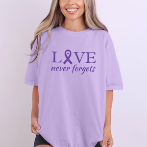 Maglietta per la sensibilizzazione sull&#39;Alzheimer &quot;Love Never Forgets&quot;, maglietta viola per l&#39;Alzheimer, regalo con nastro viola per il supporto all&#39;Alzheimer, maglietta per il supporto alla famiglia con demenza