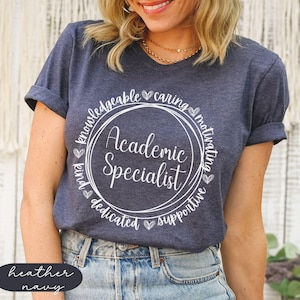May include: A heather navy blue t-shirt with a white circle graphic that says "Academic Specialist" surrounded by the words "knowledgeable, caring, motivating, kind, dedicated, supportive".