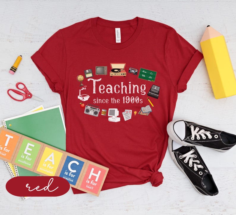 May include: Red t-shirt with a retro design featuring the text "Teaching since the 1900s" and various 1990s-themed icons. The shirt is a great gift for teachers.