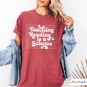 May include: Crimson-colored t-shirt with the text "Teaching Reading is a Science" in white. The shirt also features a list of related educational terms. The shirt is a comfortable, casual style.