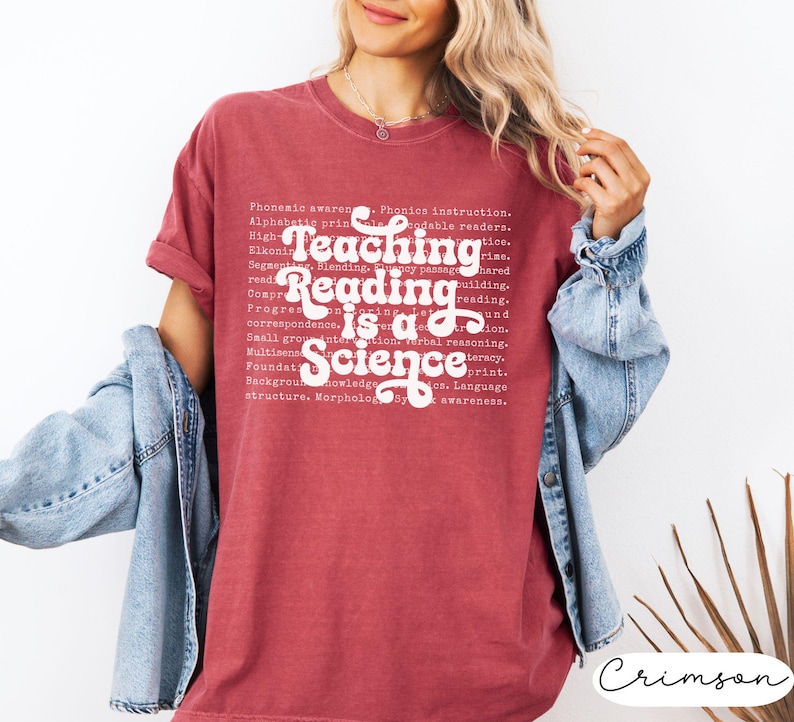 May include: Crimson-colored t-shirt with the text "Teaching Reading is a Science" in white. The shirt also features a list of related educational terms. The shirt is a comfortable, casual style.