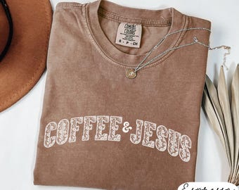 May include: A brown t-shirt with the text "COFFEE & JESUS" in white with a floral design. The shirt is made of a soft, comfortable material.