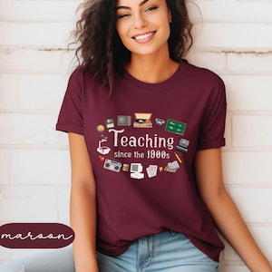 May include: A maroon t-shirt with a white graphic of various retro technology items and the text "Teaching since the 1900s".