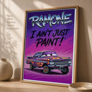 May include: A framed poster featuring a purple vintage car with orange flame decals. The text at the top reads RAMONE in a stylized font, followed by the text I AIN'T JUST PAINT! The car has large eyes on the windshield and a chrome bumper.