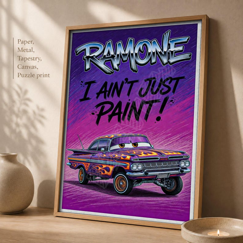 May include: A framed poster featuring a purple vintage car with orange flame decals. The text at the top reads RAMONE in a stylized font, followed by the text I AIN'T JUST PAINT! The car has large eyes on the windshield and a chrome bumper.