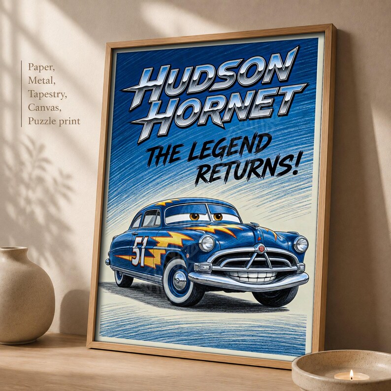 May include: A framed poster featuring a blue Hudson Hornet race car with yellow lightning bolt graphics and the number 51. The text reads HUDSON HORNET THE LEGEND RETURNS! The background has a blue and cream sketch-like texture with a light wood frame.