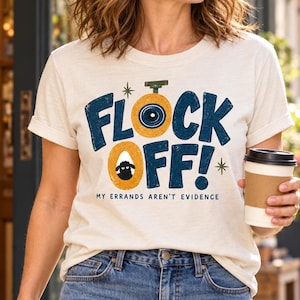 May include: A cream-colored short-sleeve t-shirt featuring the dark blue text FLOCK OFF! with a yellow circular graphic containing a black sheep illustration and the smaller text MY ERRANDS AREN'T EVIDENCE printed below the main design.