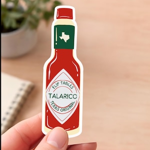 Puede incluir: Una pegatina roja y blanca con forma de botella de salsa picante. La pegatina dice "TALARICO TEXAS ORIGINAL" con las palabras "FLIP TABLES" encima del nombre de la marca. La parte superior de la botella tiene una etiqueta verde con el contorno blanco de Texas.