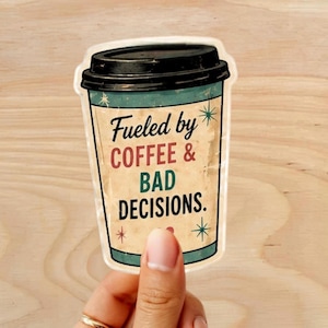 Może przedstawiać: Naklejka w kształcie kubka do kawy z czarną pokrywką. Naklejka zawiera tekst "Fueled by COFFEE & BAD DECISIONS." w kolorze czarnym i czerwonym. Kubek jest beżowy z turkusową obw&oacute;dką i gwiazdkami.